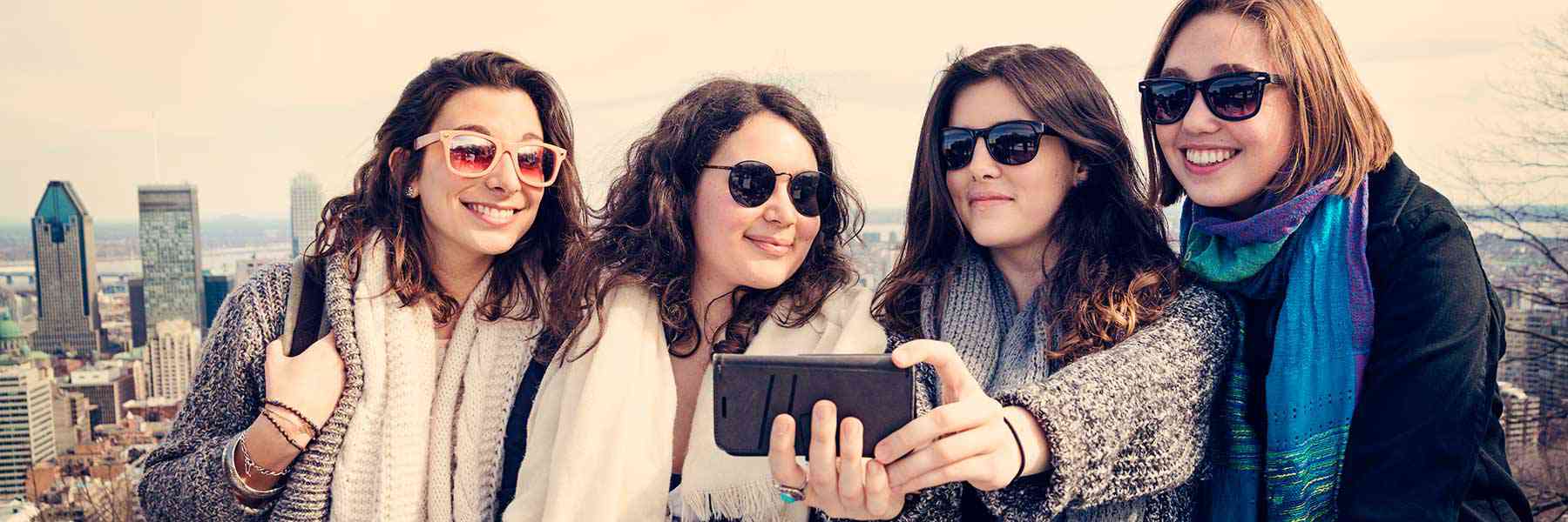 Image d'une groupe de jeunes femmes prenant un égoportrait avec le paysage urbain en arrière-plan